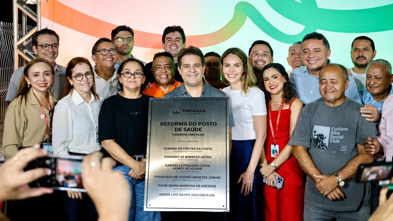 O prefeito Evandro Leitão, a vice Gabriella Aguiar e uma grande quantidade de pessoas estão em volta da placa do posto de saúde recém descerrada
